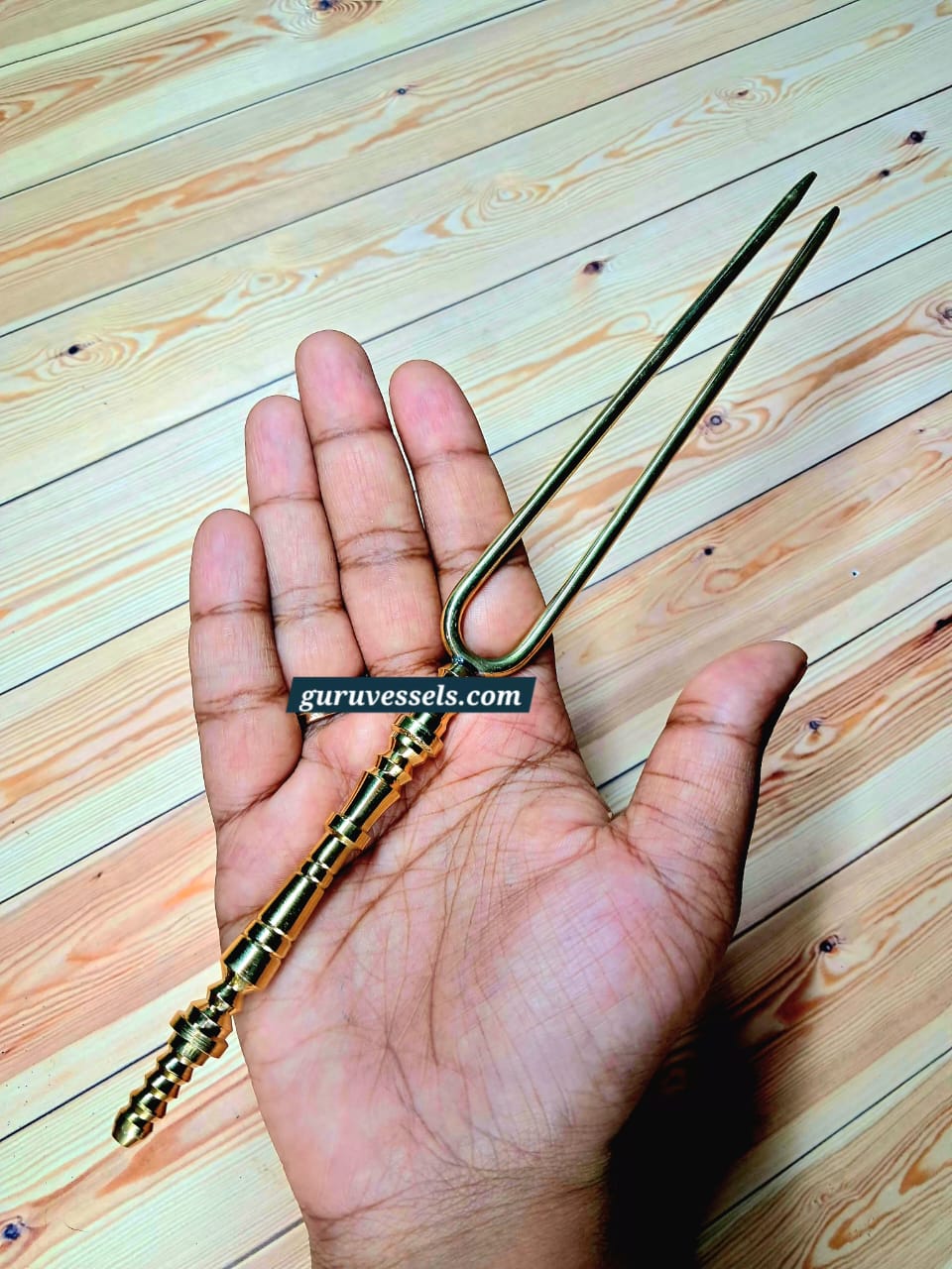 Original product photo of a premium pure brass hair detangler held in hand, showing its size, traditional handle and smooth detangling prongs