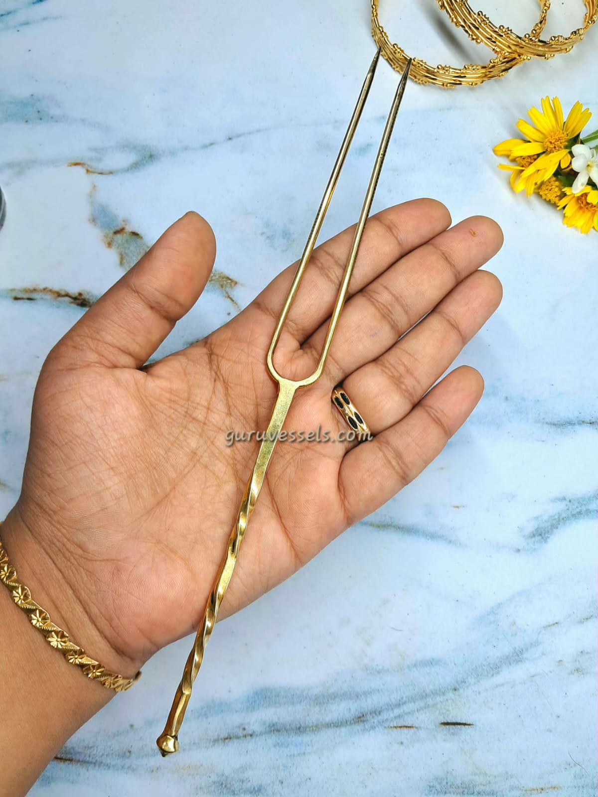 Gold hair detangler held in a hand with a marble background